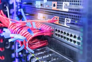 Close-up of network switches with organized red Ethernet cables in a data center.