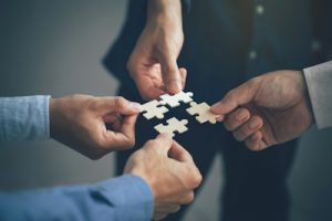 Four hands collaboratively assembling puzzle pieces, symbolizing the partnership and teamwork of Co-Managed IT services that strengthen internal IT teams with scalable support and additional resources.